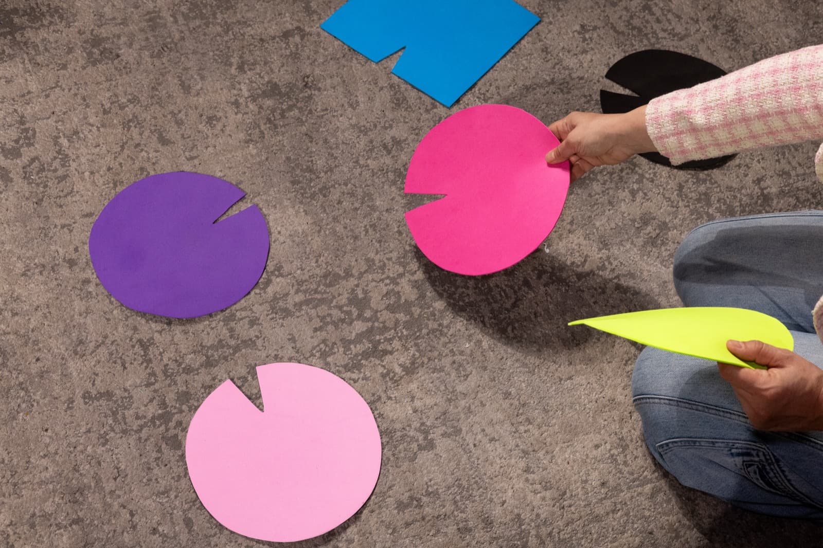 Coloured lily-pad shaped markers laid out on the floor during a constellation, hands placing them